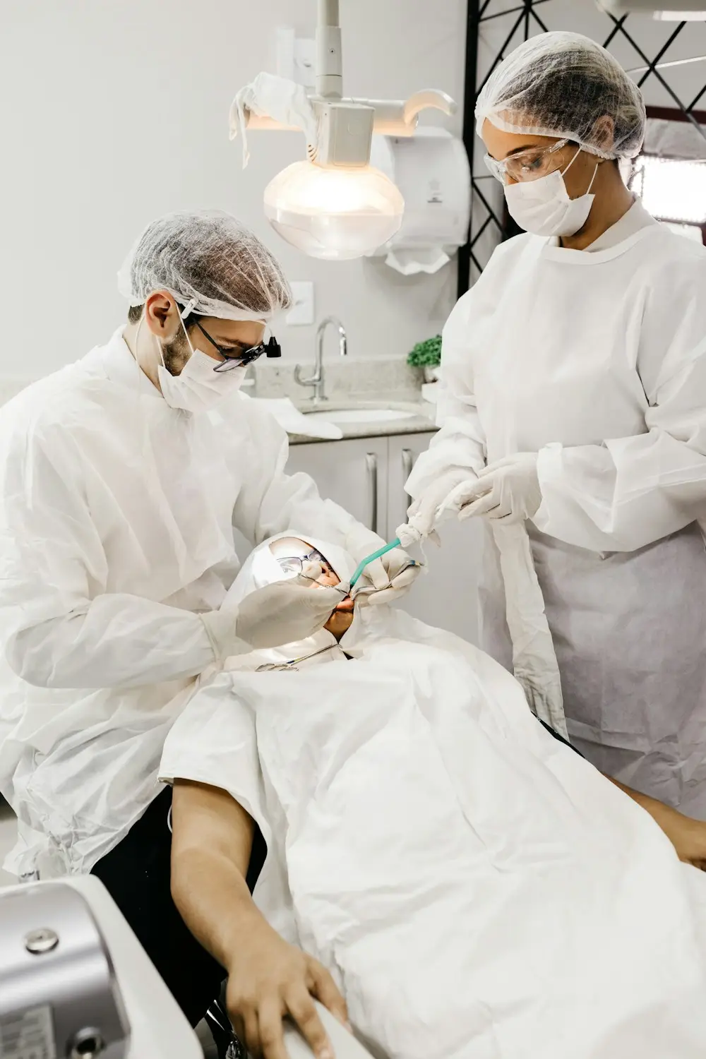 Dos dentistas con equipo de protección atendiendo a un paciente