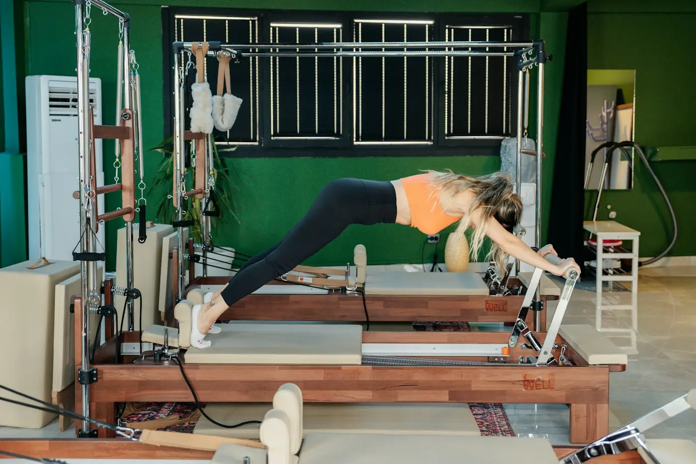 Mujer estirándose de lado sobre un reformer de pilates
