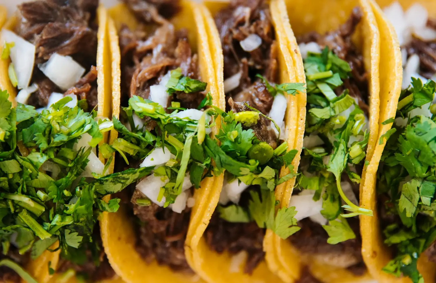 Tres tacos de res con cebolla picada y cilantro